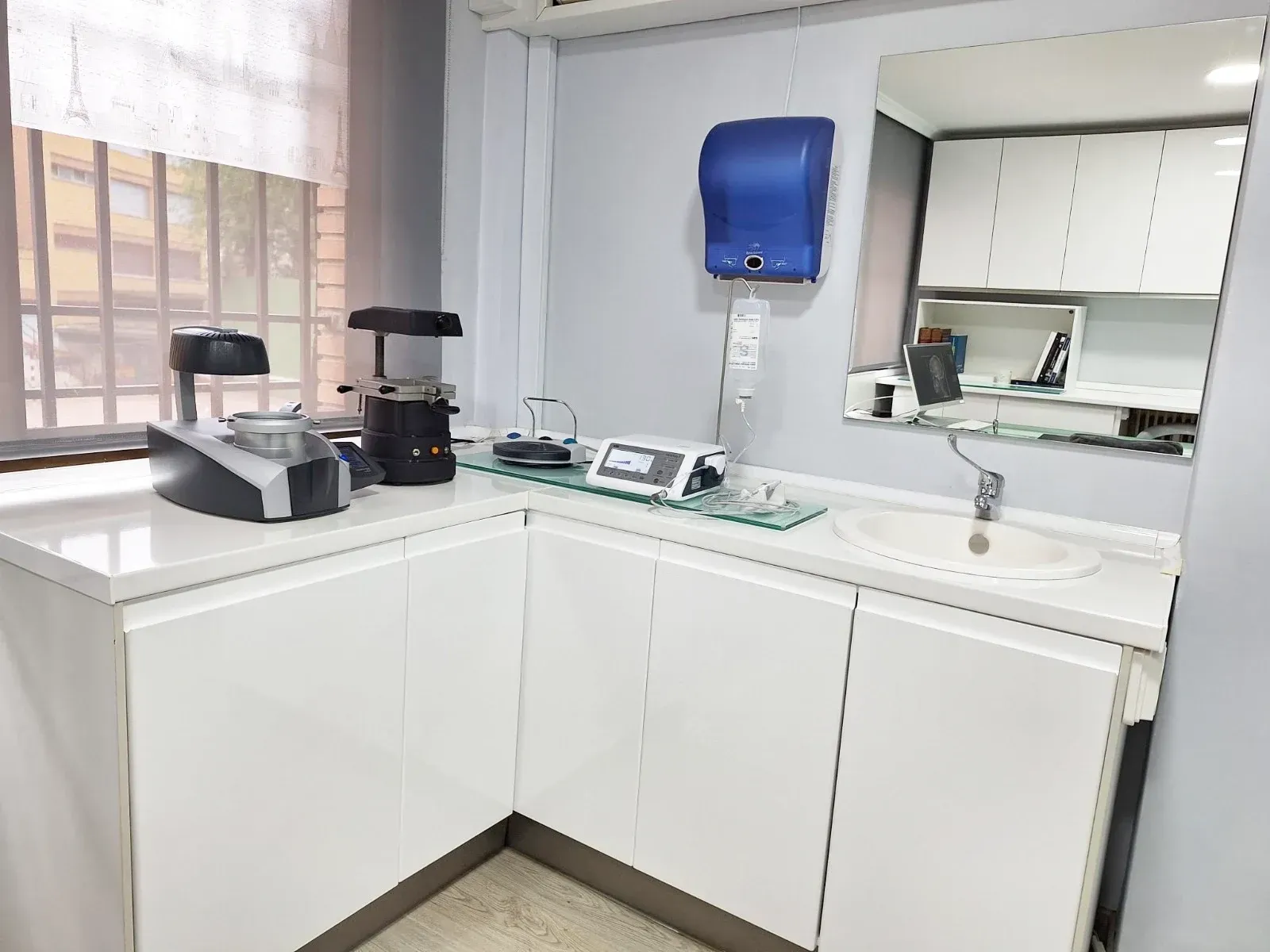 Una cocina con muebles blancos, un fregadero y un espejo.