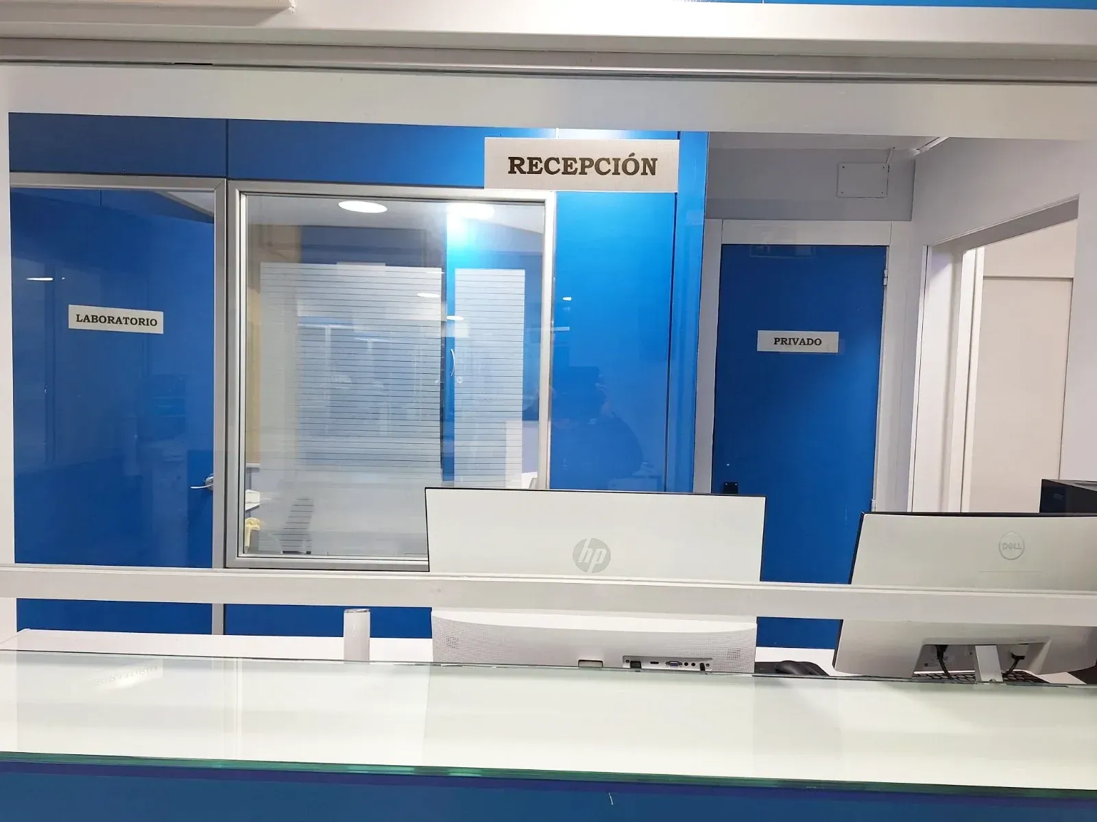 Un área de recepción en un hospital con paredes azules y escritorios blancos.