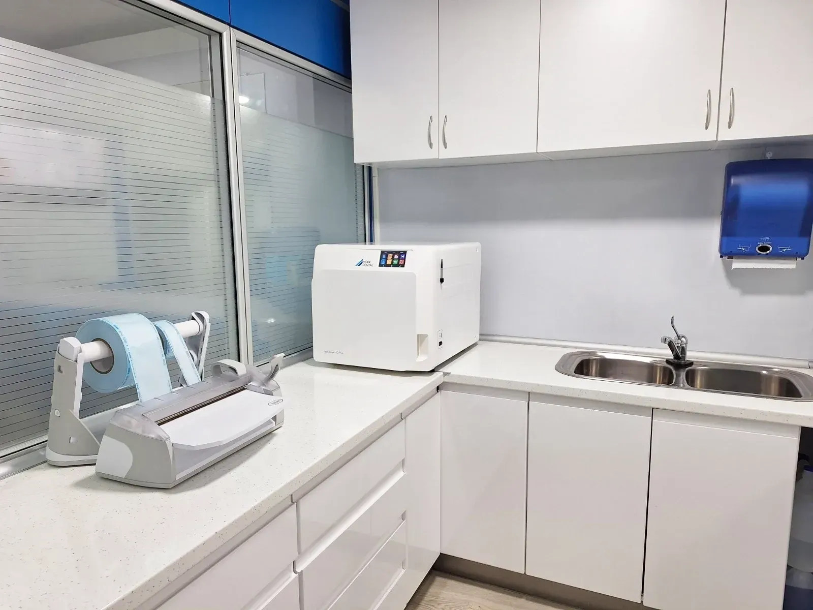 Una cocina con gabinetes blancos, un fregadero y un microondas.